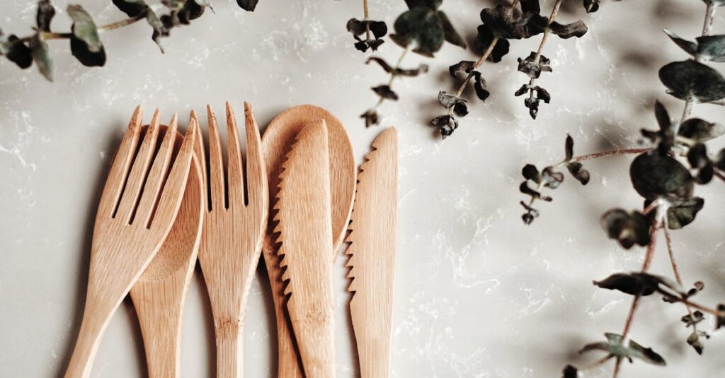 Close-up of bamboo utensils and eucalyptus branches on a marble surface, highlighting sustainability.
