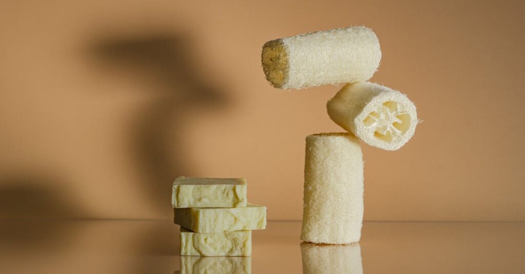Minimalist arrangement of organic soap bars and loofahs on reflective surface.